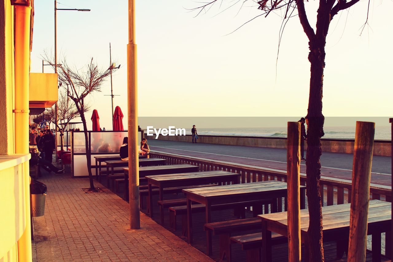 Bench and tables at outdoor cafe against sky