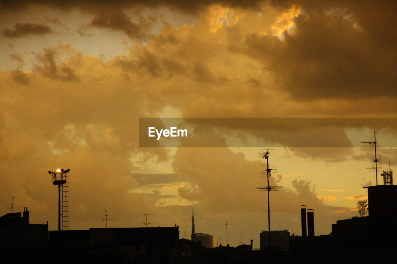 High section of silhouette building against cloudy sky