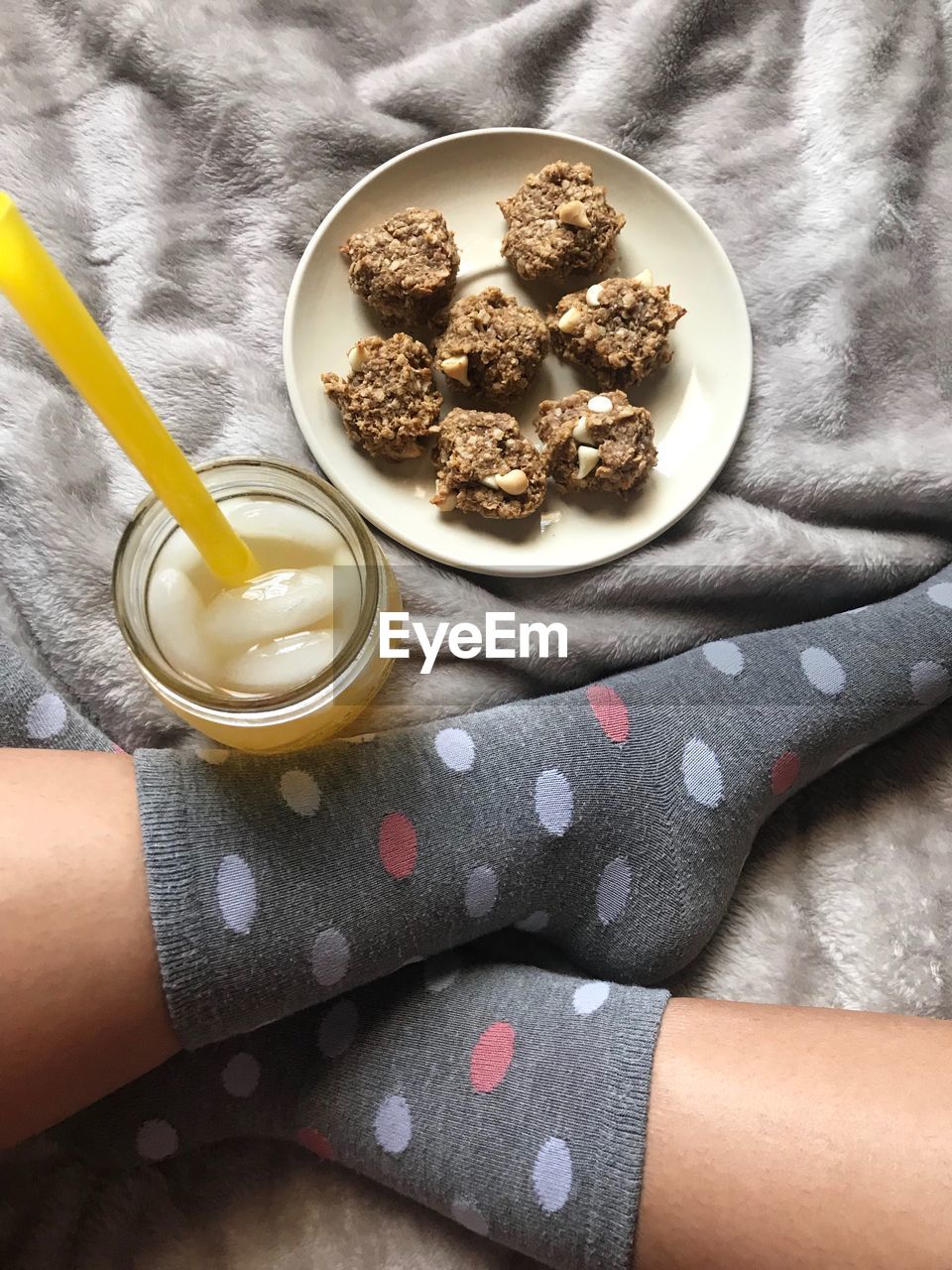Low section of woman wearing socks while sitting by food in plate on bed