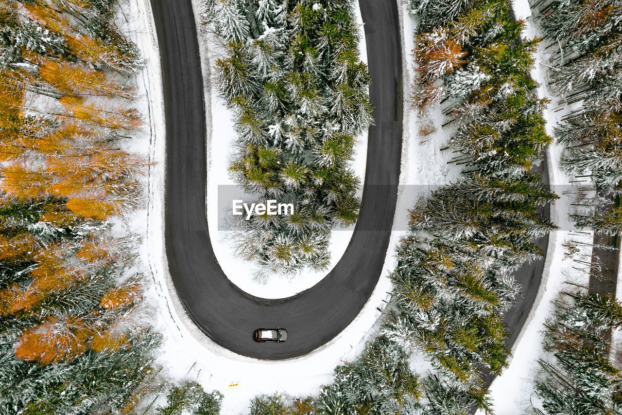 Aerial view of car on winding road in winter forest