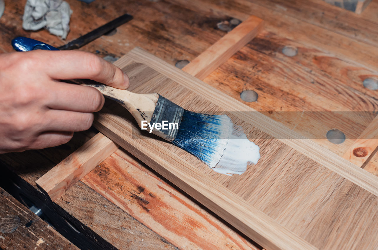 Varnishing a wooden drawer, carpentry workshop. varnish is applied to a wooden board with a brush