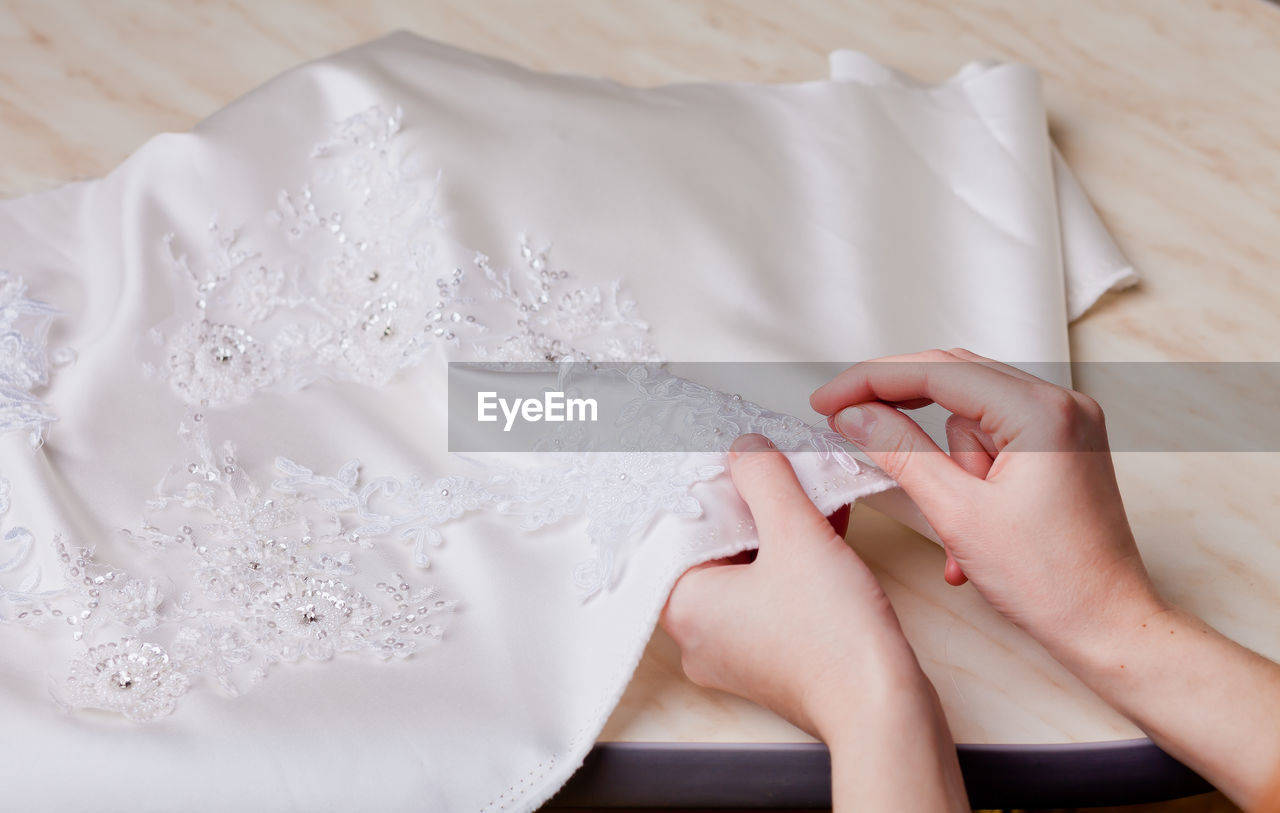 Cropped hands of woman stitching wedding dress