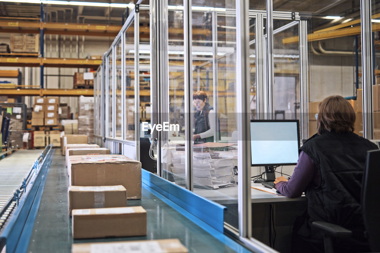 Two women in storehouse with packages on conveyor belt