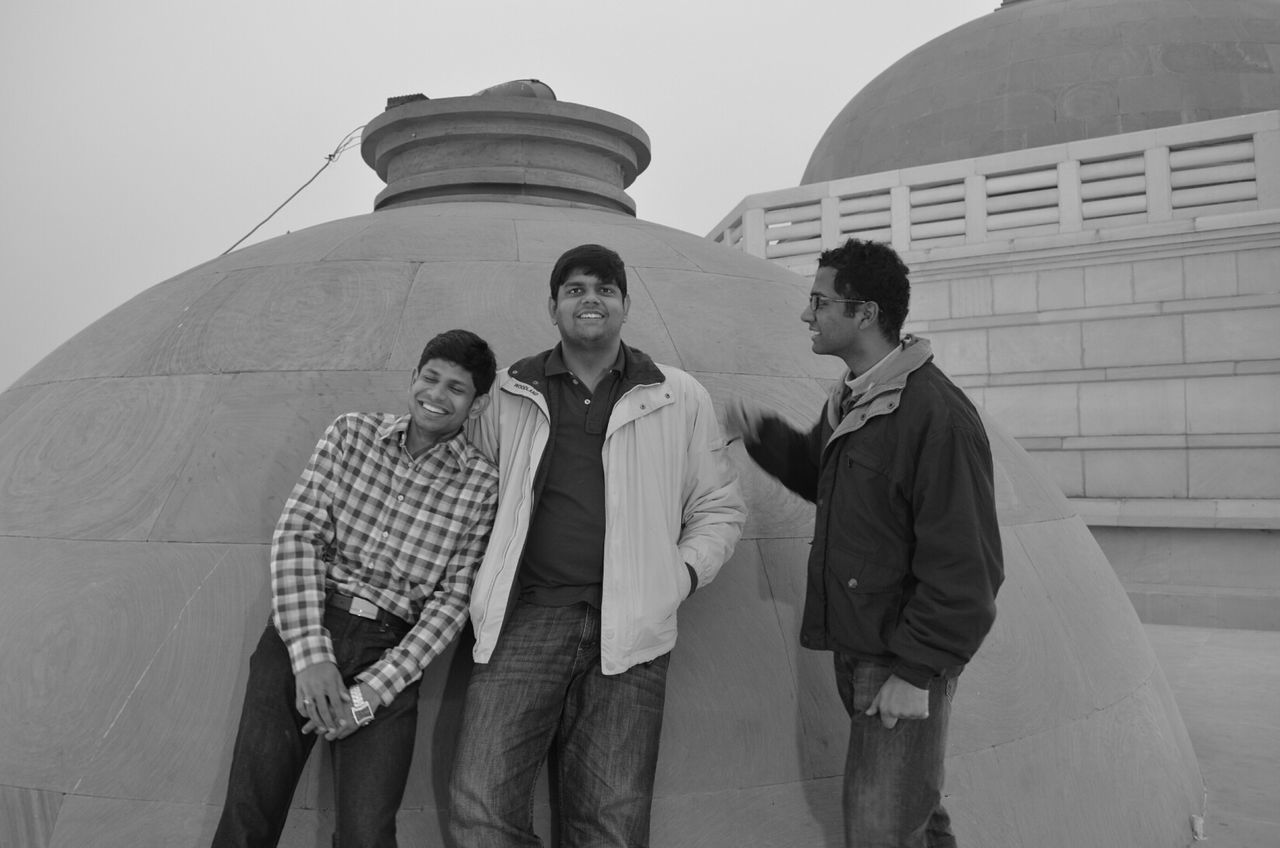 Happy friends at temple against clear sky