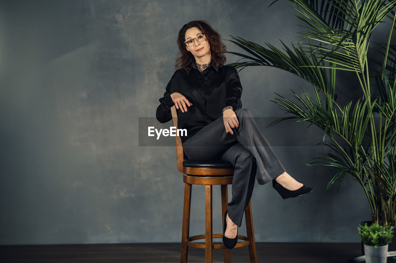 Business woman sitting cross-legged on a high chair