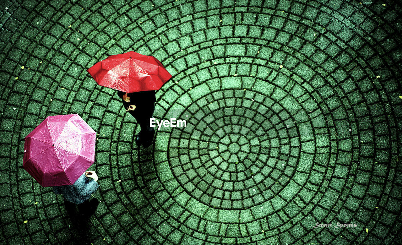 High angle view of people with umbrellas standing on footpath during monsoon