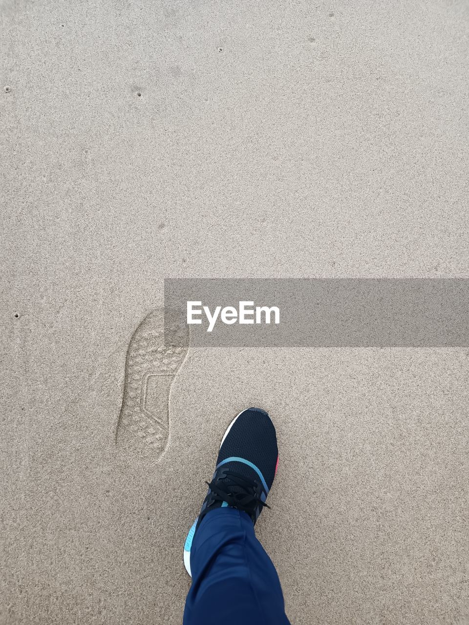 low section, human leg, shoe, one person, personal perspective, high angle view, white, blue, standing, land, day, sand, lifestyles, beach, leisure activity, black, nature, men, human limb, outdoors, limb, directly above, hand, shadow, human foot, footwear