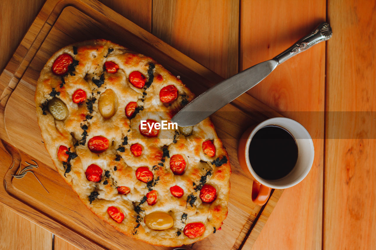 Homemade italian focaccia slices, with tomato and olive oil and a cup of coffee.