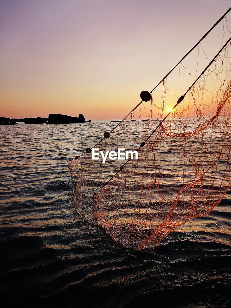 SILHOUETTE FISHING ROD ON SEA AGAINST SKY DURING SUNSET