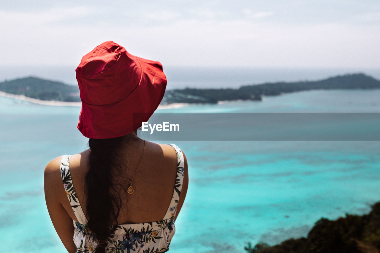 Rear view of woman wearing hat looking at sea against sky