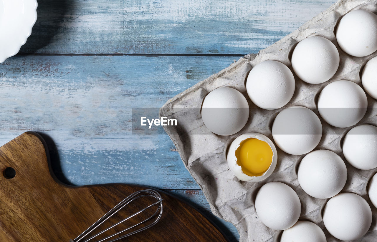 Top view of a tray of white eggs on a blue wooden table