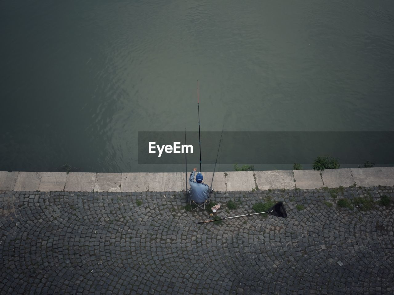 HIGH ANGLE VIEW OF MAN FISHING ON LAKE