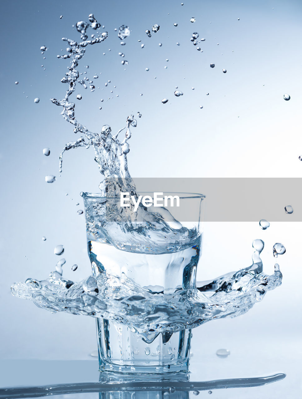 Close-up of water splashing in drinking glass against white background