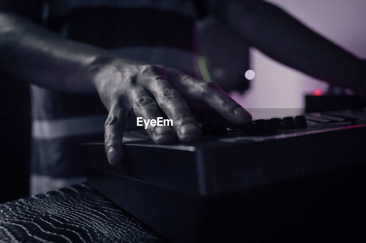 Midsection of man playing electric piano at home