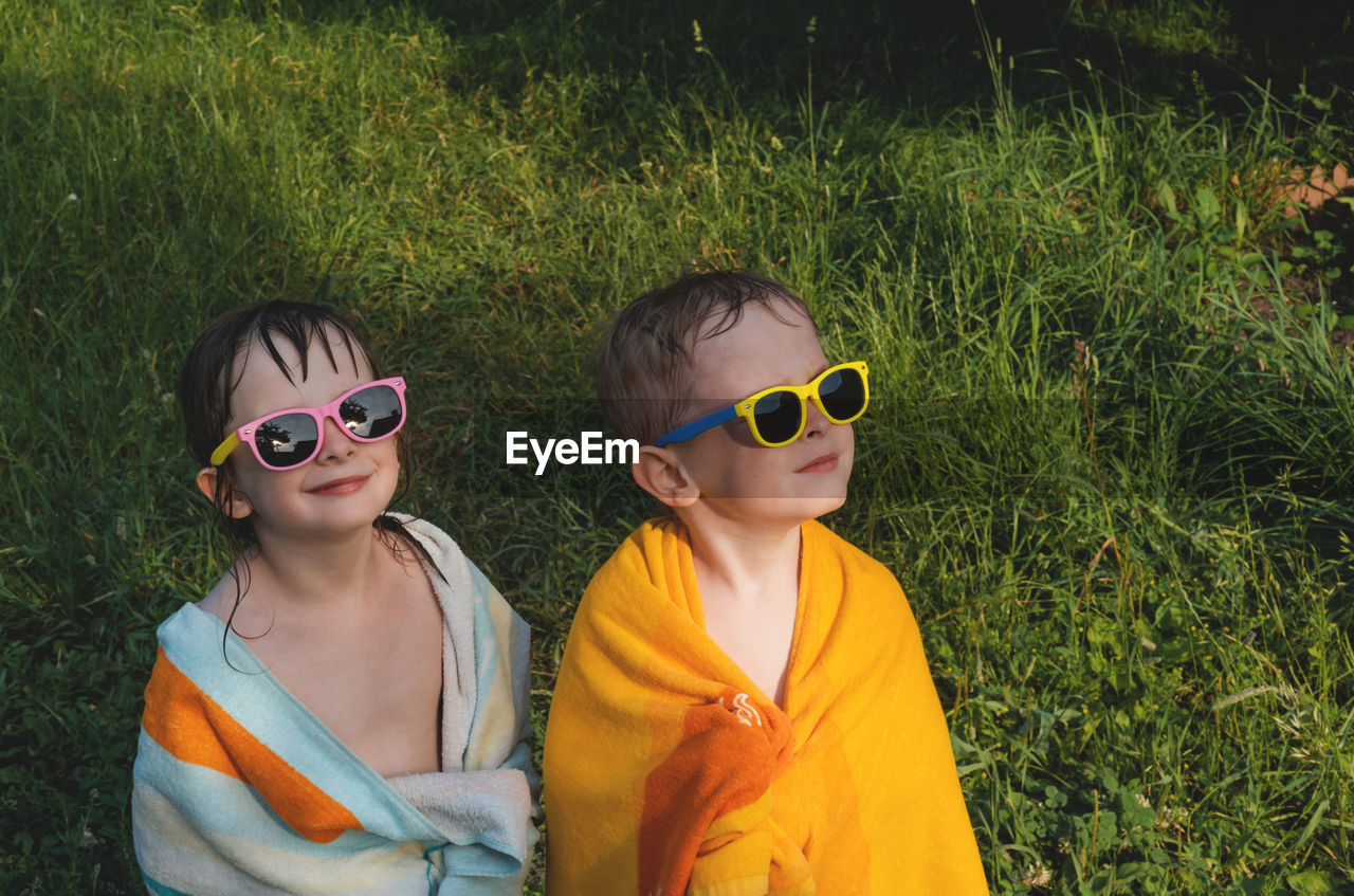 Wet cheerful children in sunglasses in a towel. boy and girl look away. 