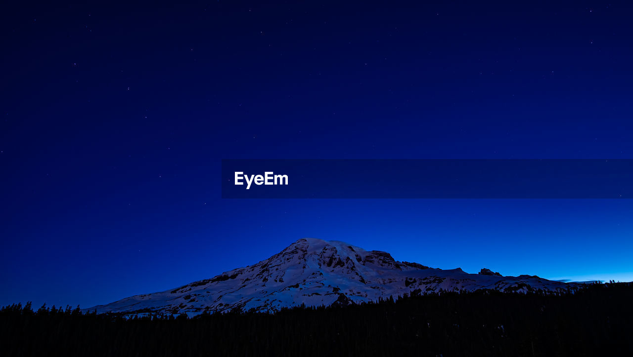 Scenic view of snowcapped mountains against clear blue sky at night