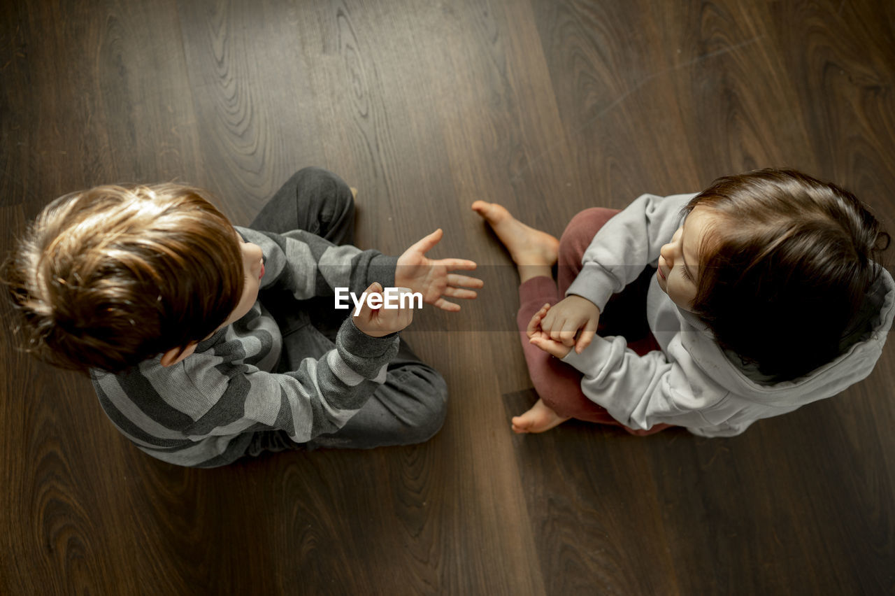 Boy with brother playing rock paper scissors on floor at home