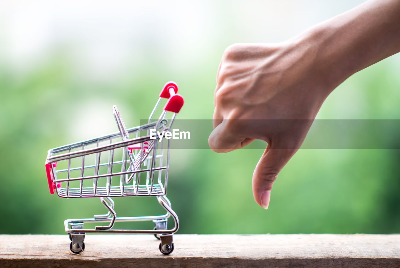 Close-up of woman gesturing by figurine shopping cart 