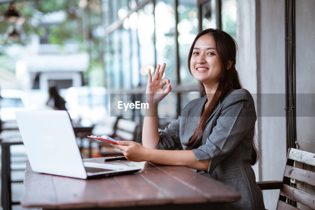 portrait of young woman using laptop while sitting on table