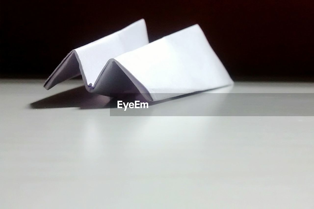 Paper airplane on table against wall