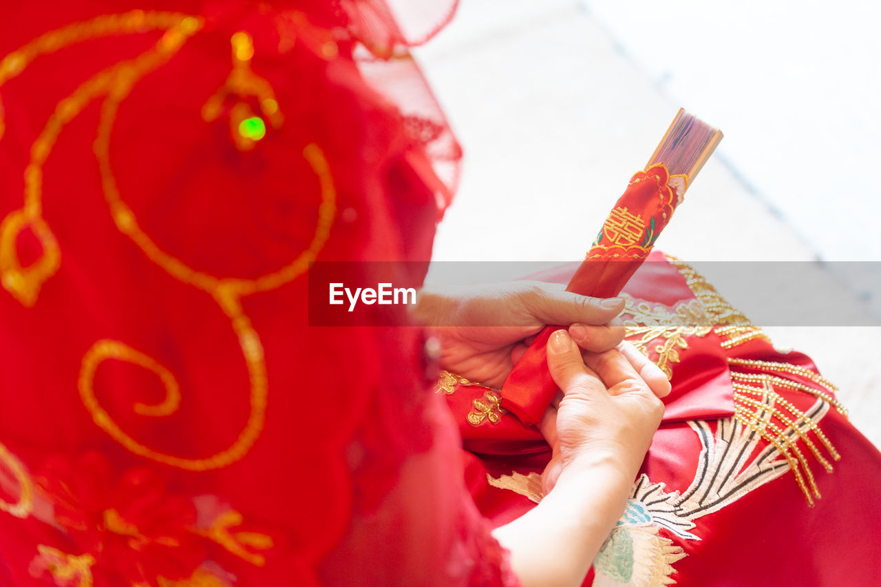 CLOSE-UP OF WOMAN HOLDING RED AND HAND WITH UMBRELLA