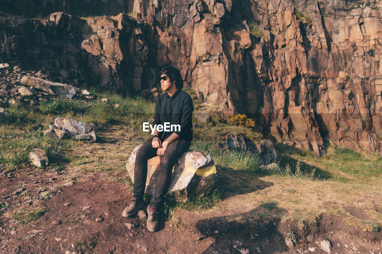 Man sitting on rock against mountain