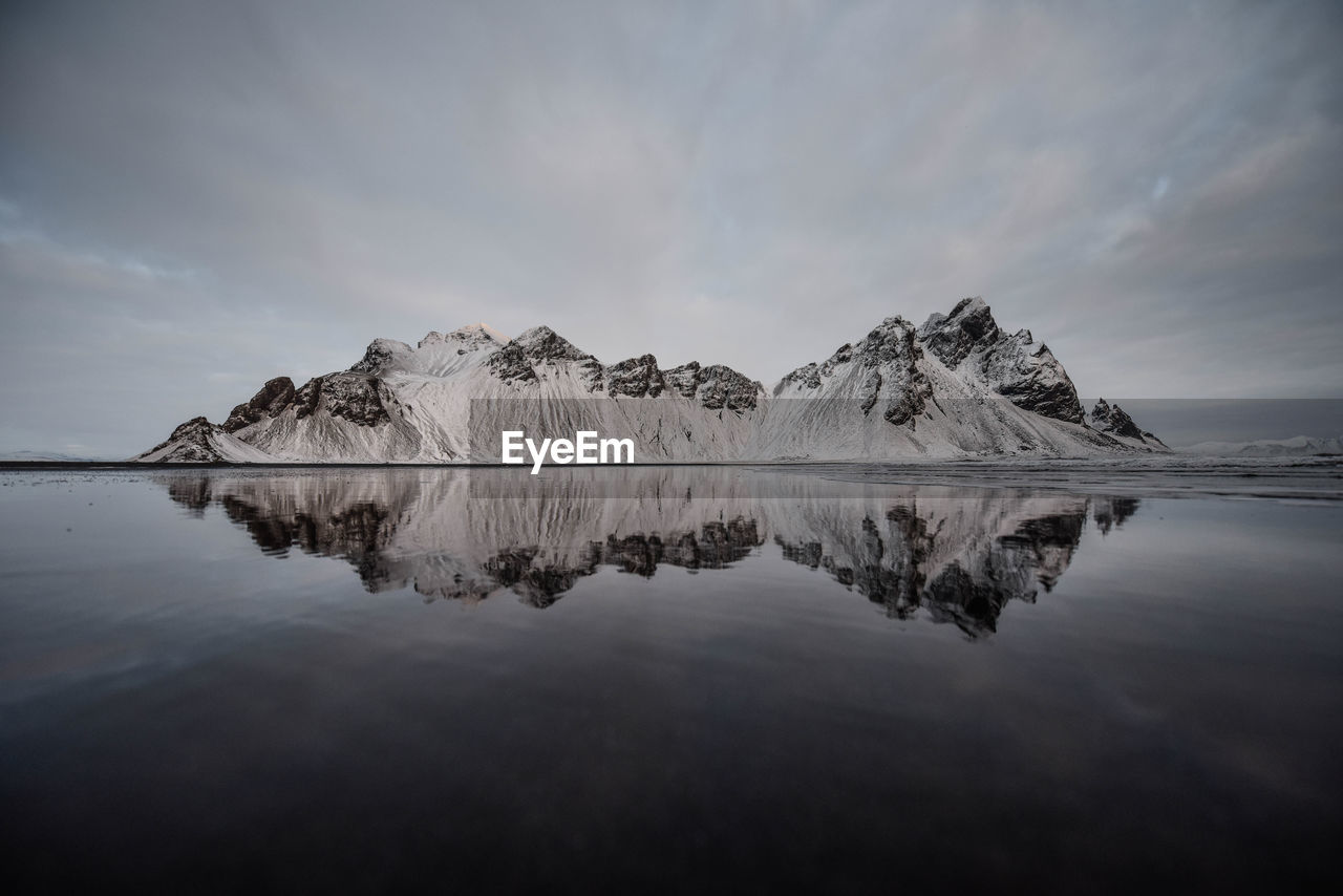 Scenic view of lake by snowcapped mountain against sky