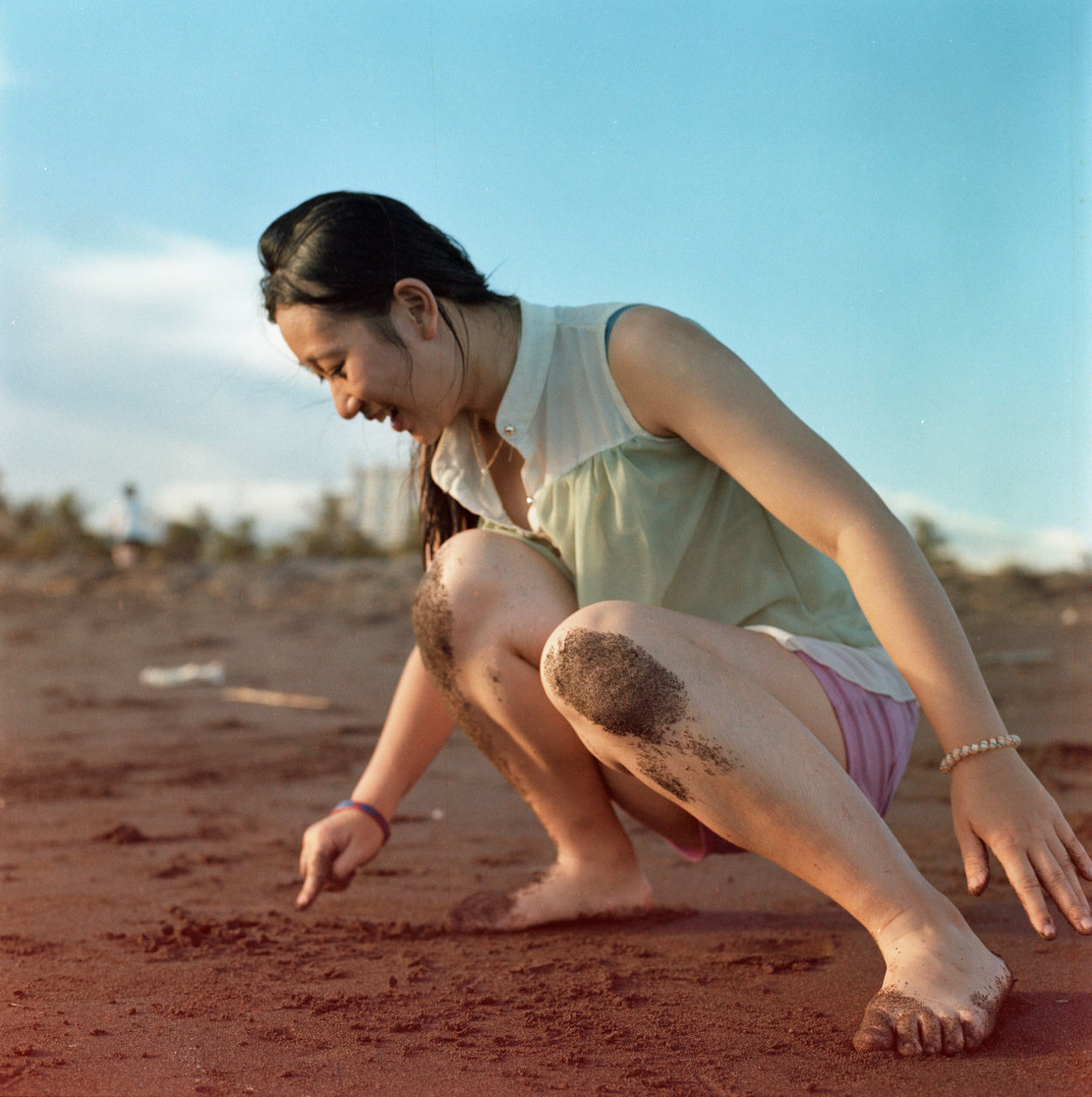 Full length of smiling woman playing with sand at beach