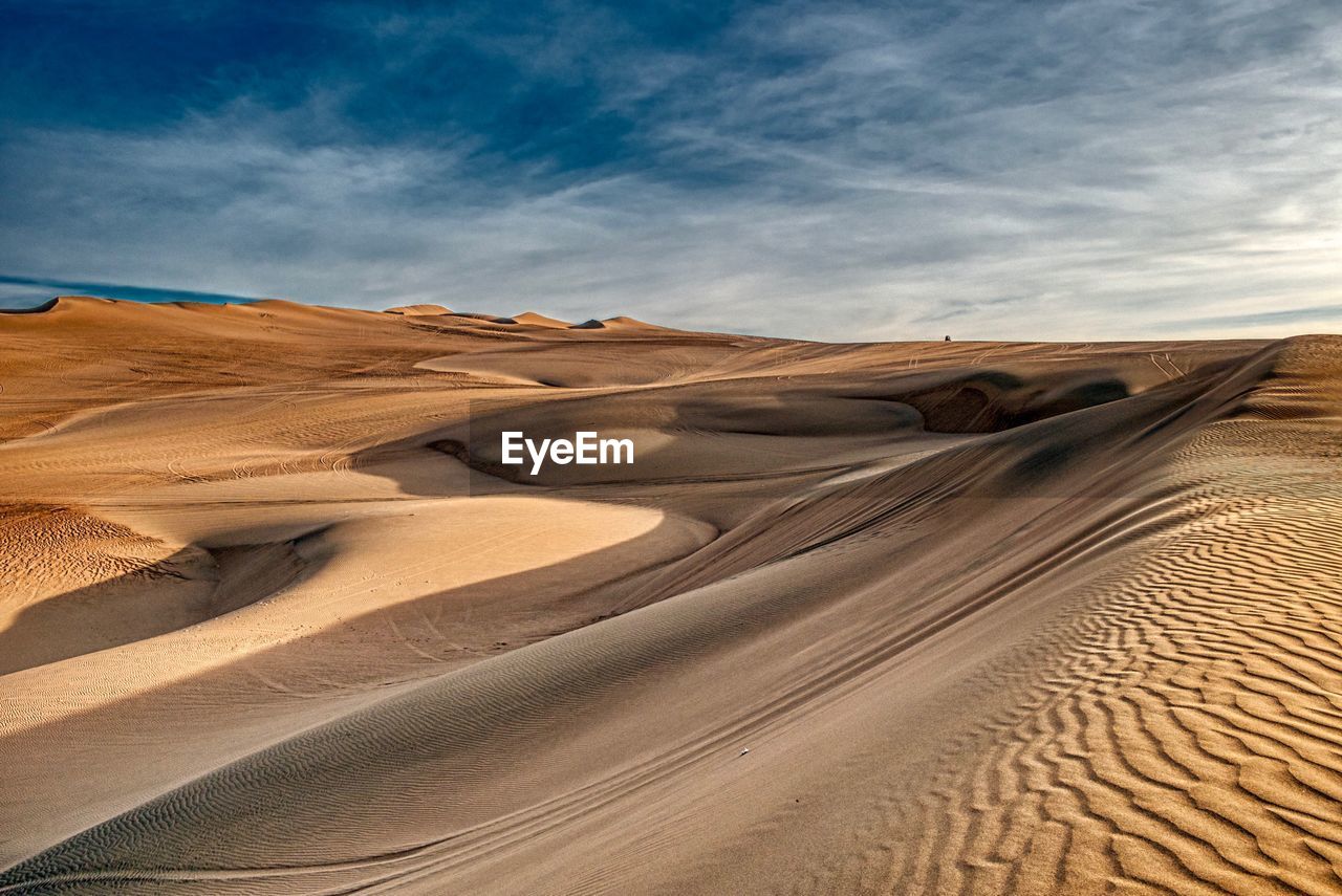 Sand dunes in desert against sky