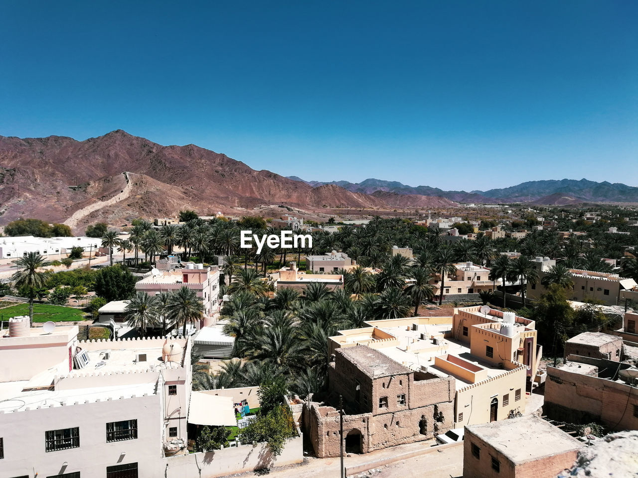 Aerial view of townscape against clear blue sky during sunny day