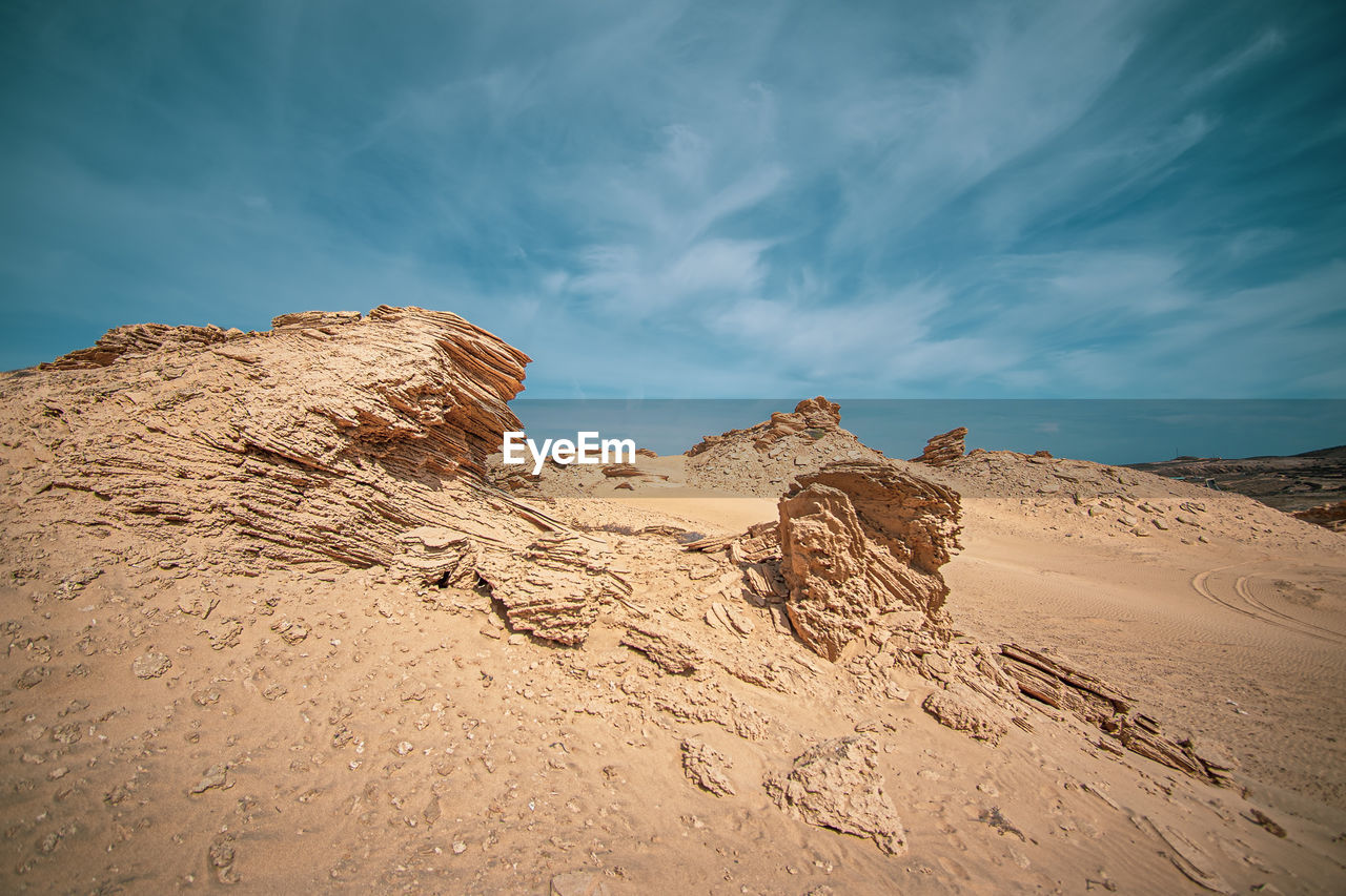 Rock formation on beach against sky