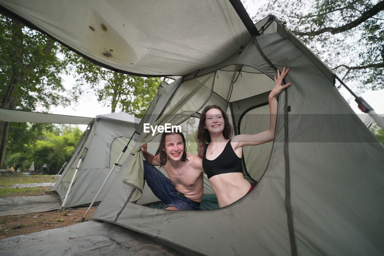 adult, tent, togetherness, two people, women, smiling, lifestyles, happiness, bonding, leisure activity, young adult, enjoyment, men, emotion, day, female, casual clothing, friendship, portrait, nature, fun, front view, tree, cheerful, architecture, outdoors, carefree, relaxation, positive emotion, person, looking at camera, holiday, full length, love, trip, weekend activities, vitality, human face, vacation, clothing