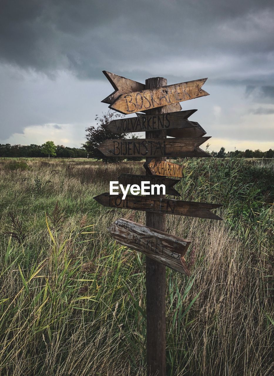 Wooden information sign on field against sky