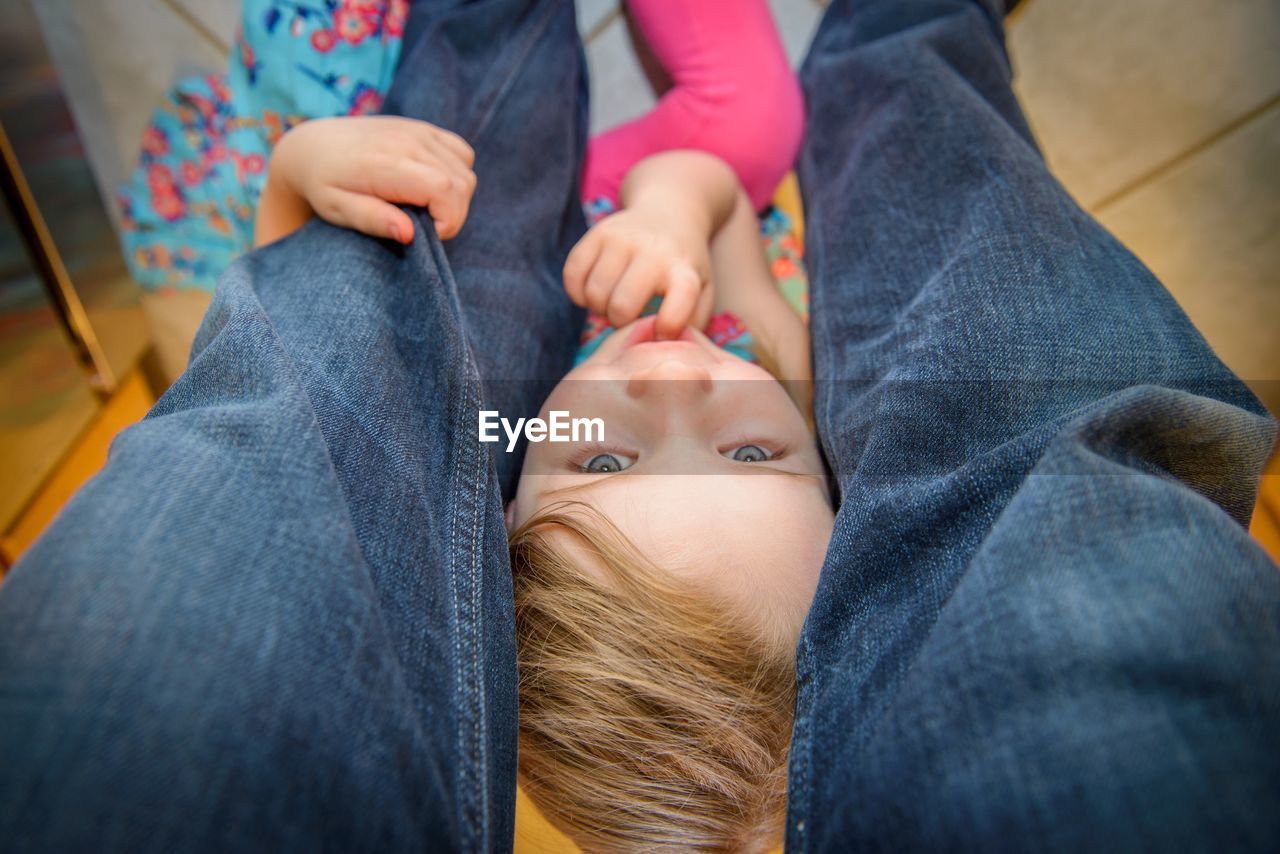 Midsection of girl sitting amidst father legs