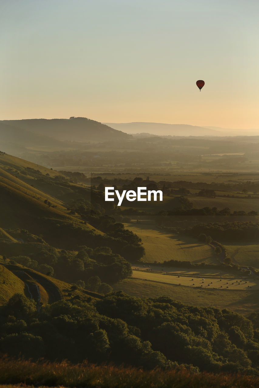 Hot air balloon flies at sunset over devil's dyke in the south downs, near brighton, east sussex, uk