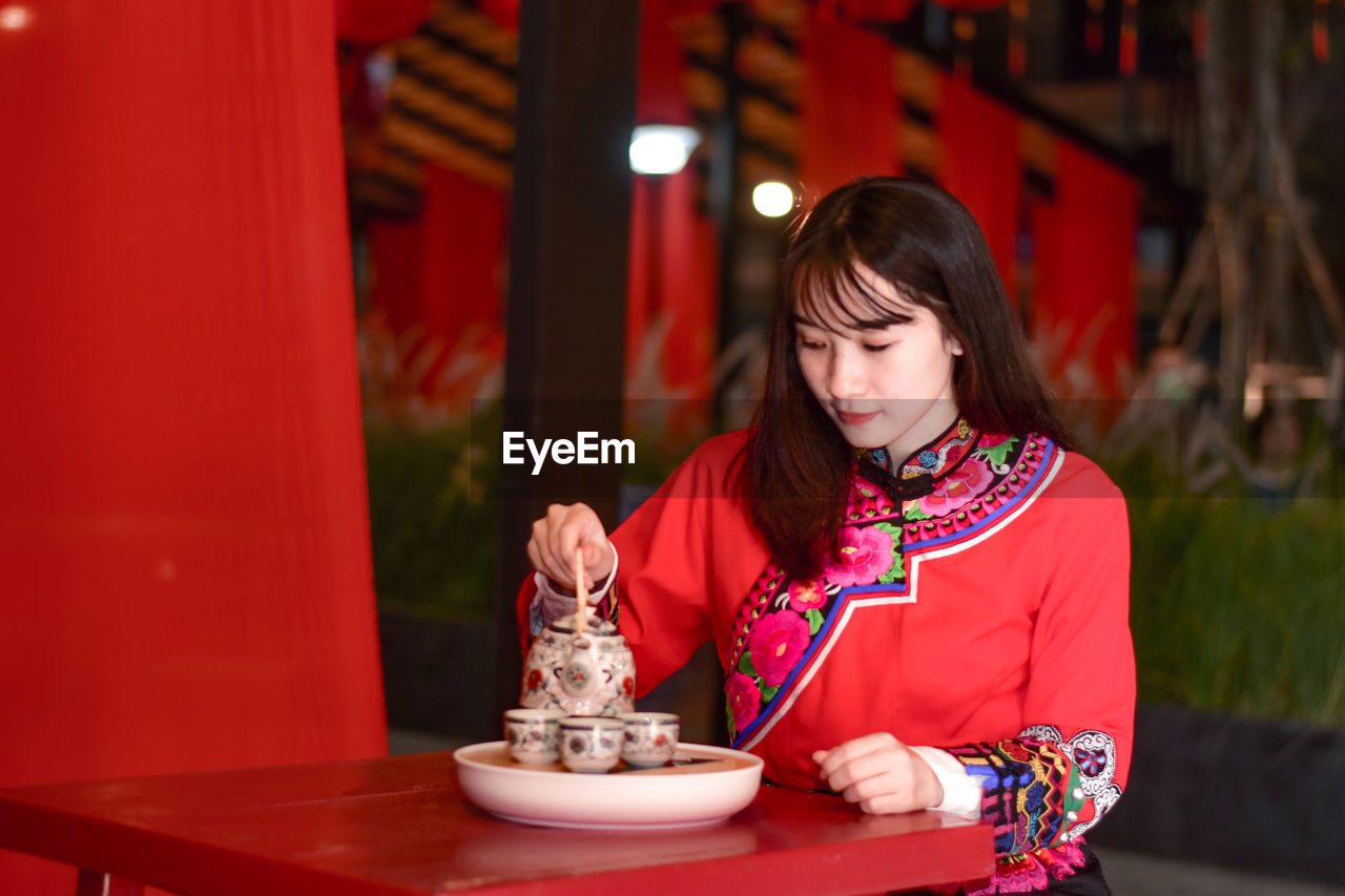 Woman looking away while sitting on table