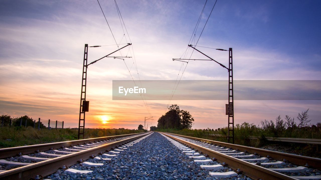 RAILROAD TRACK AGAINST SKY DURING SUNSET