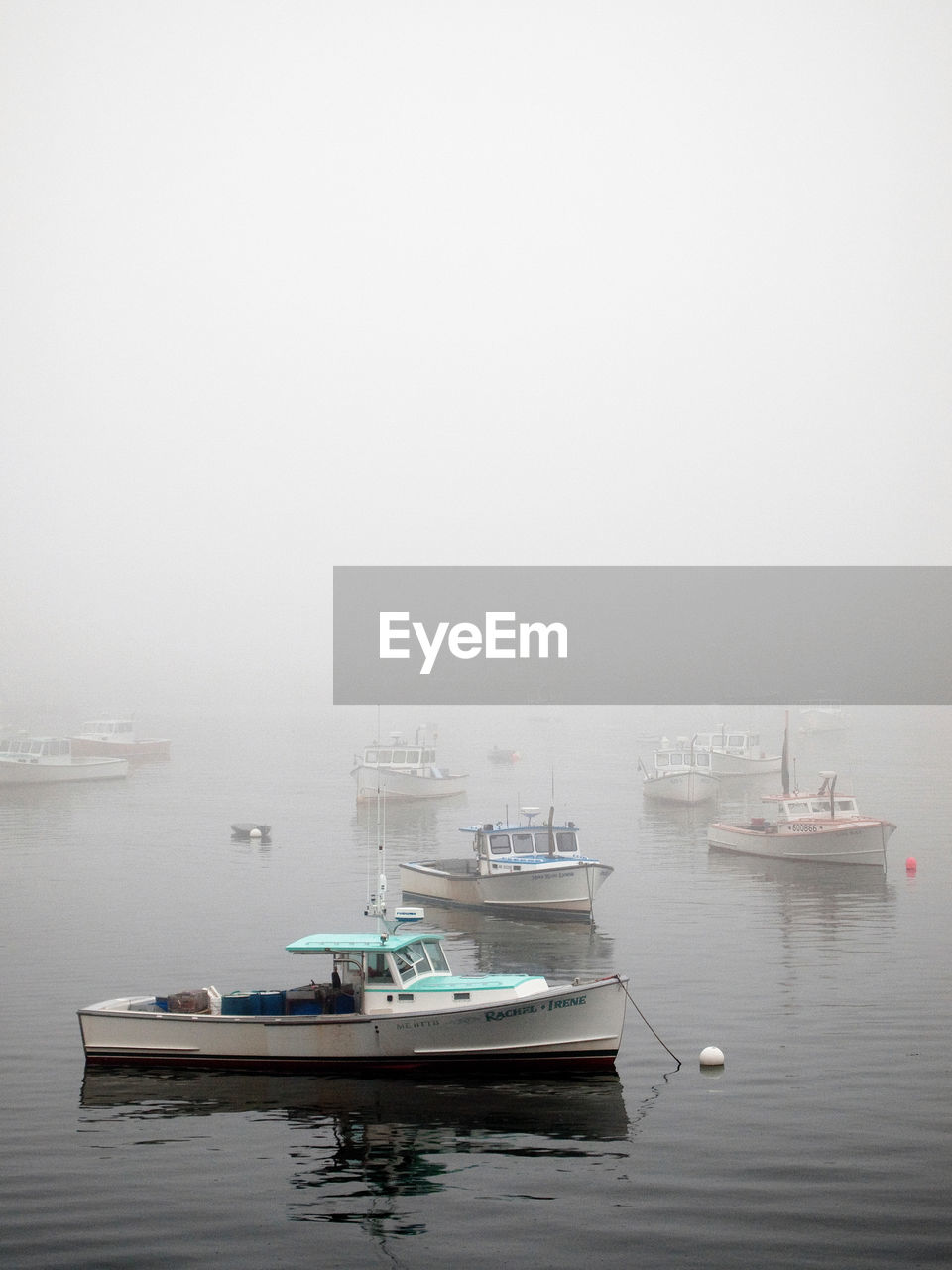 BOATS MOORED ON HARBOR AGAINST SKY