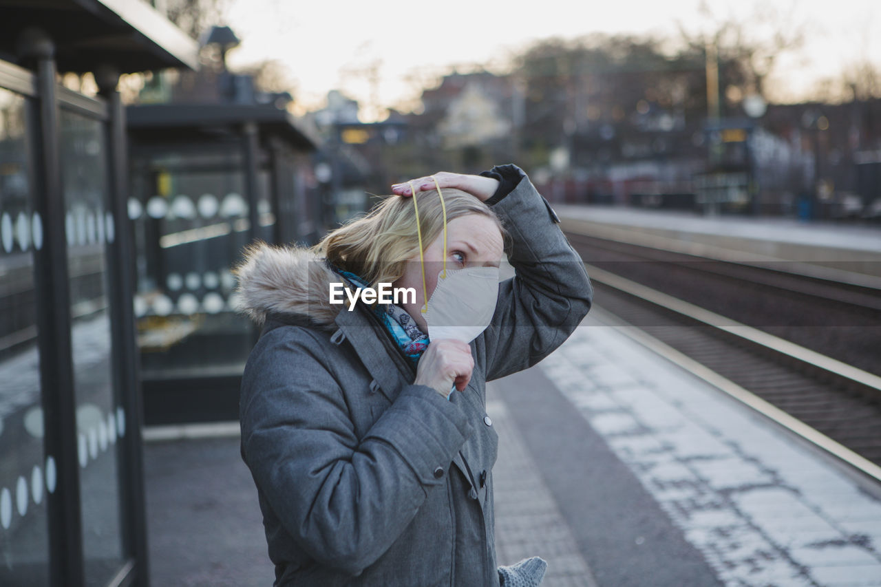 Woman wearing protective mask on train station platform