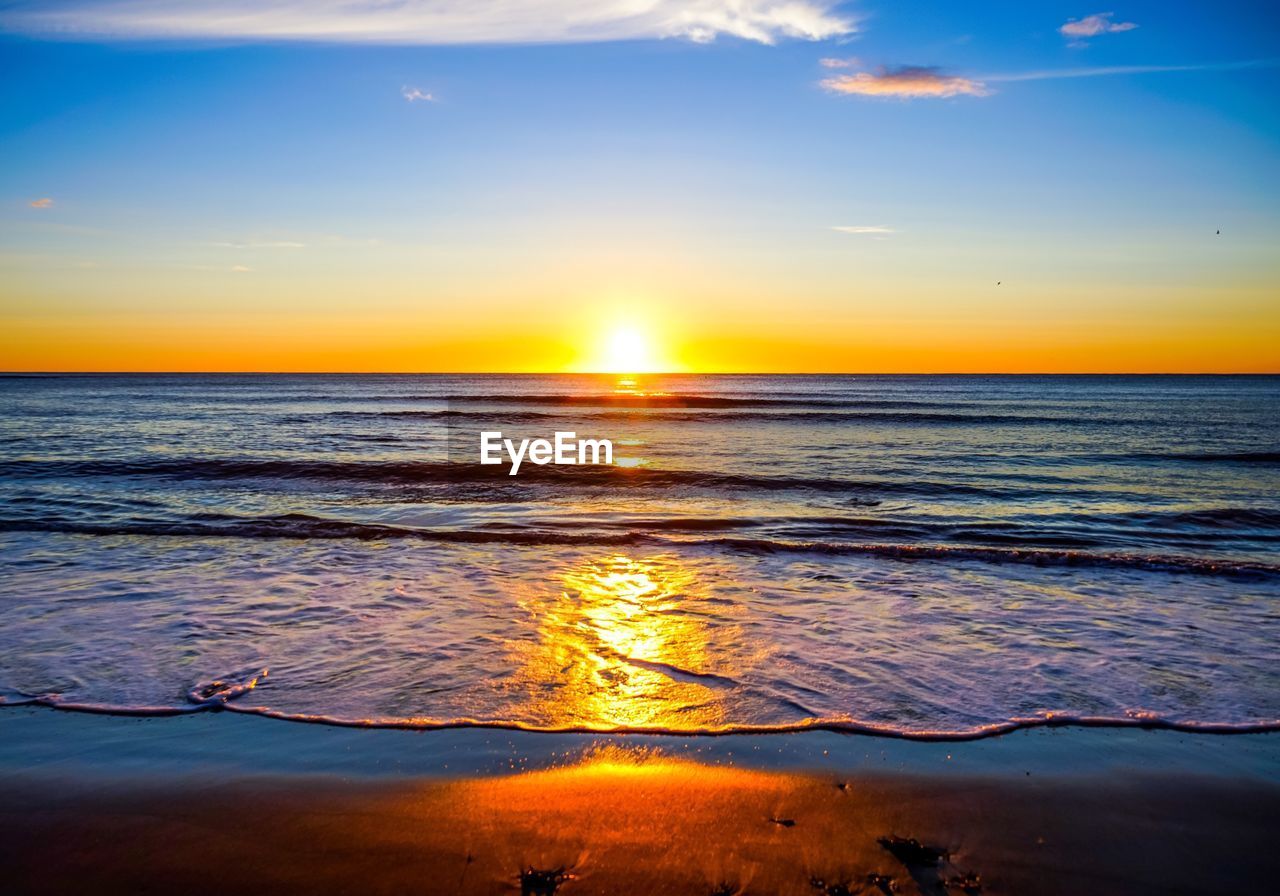 SCENIC VIEW OF BEACH AGAINST SKY DURING SUNSET