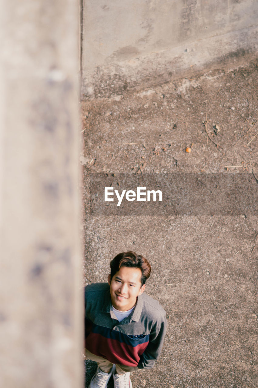 Portrait of smiling man standing by wall outdoors