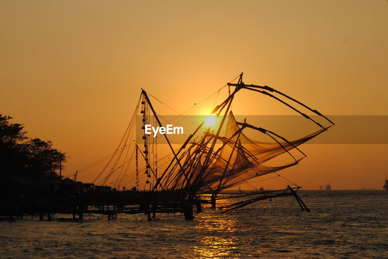 Side view of boats in sea at sunset