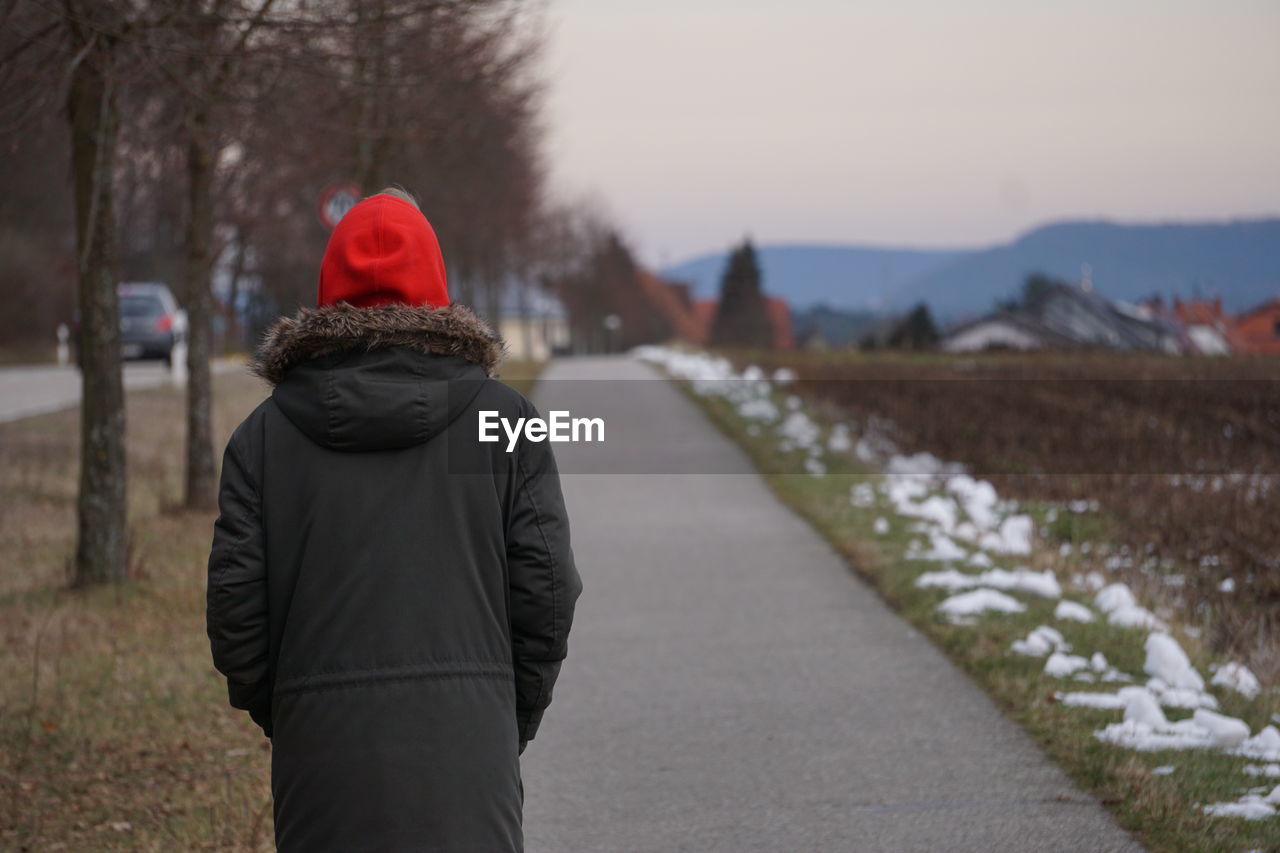 Rear view of man standing on road during winter