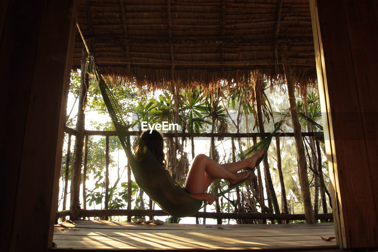 Side view of woman sitting on hammock