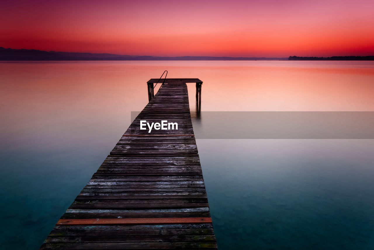 Pier over lake against sky during sunset