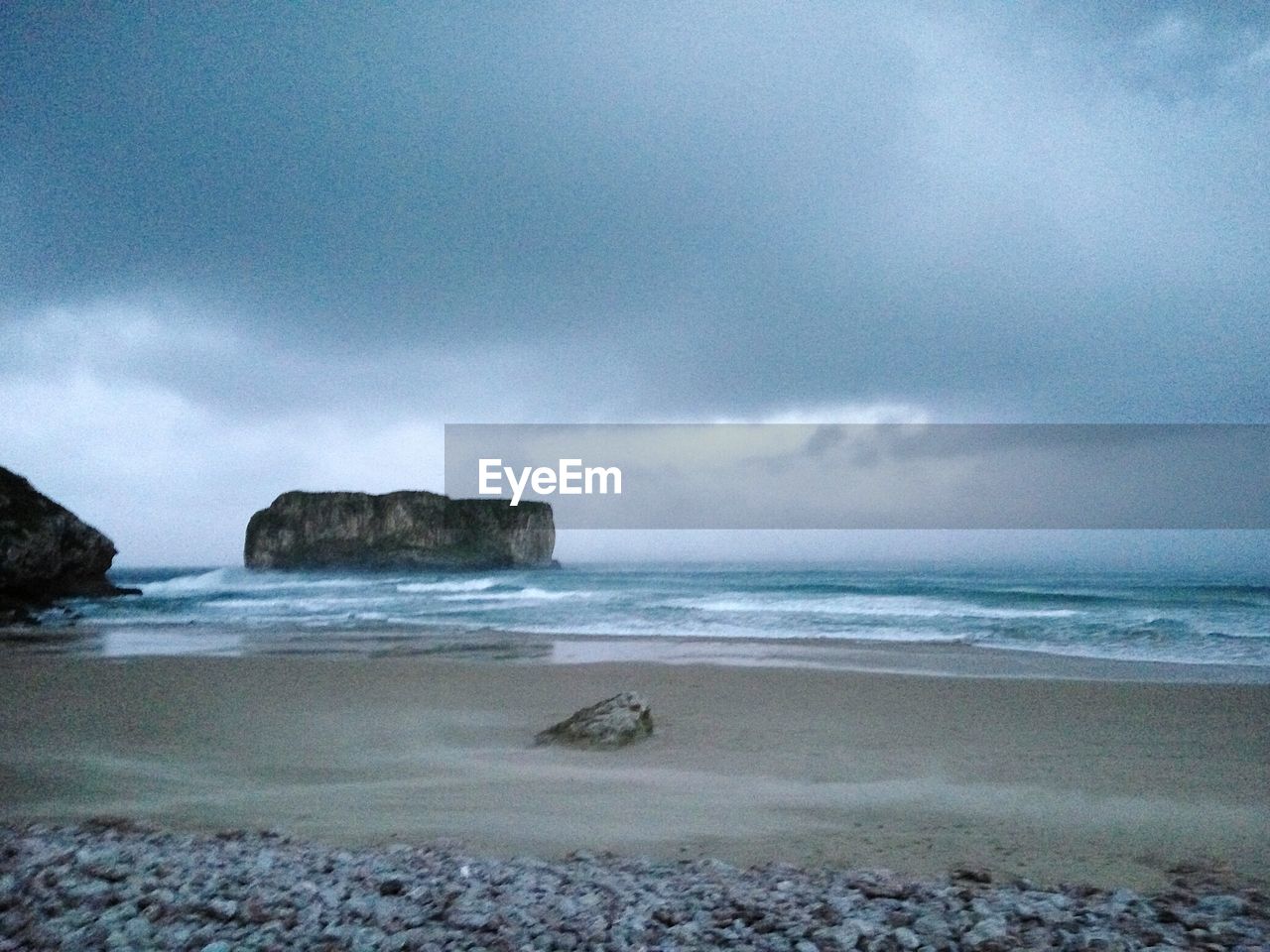 Scenic view of beach against cloudy sky