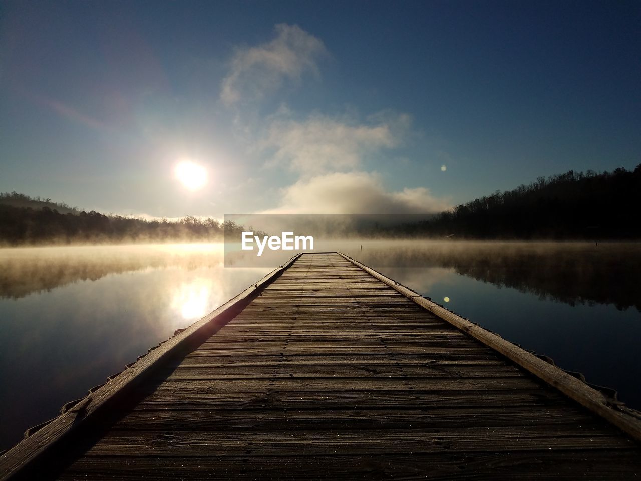 Pier over lake against sky during sunset