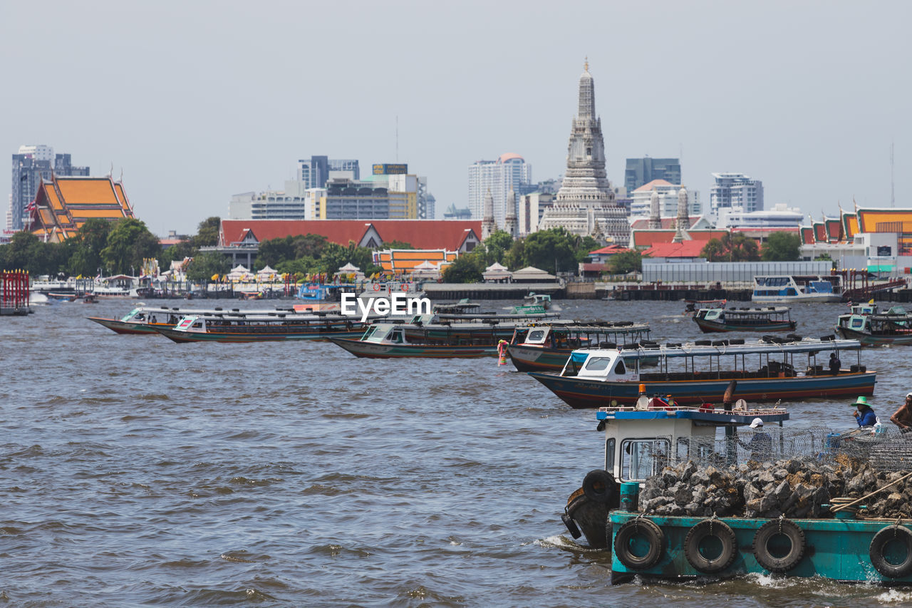 BOATS IN SEA BY BUILDINGS AGAINST SKY