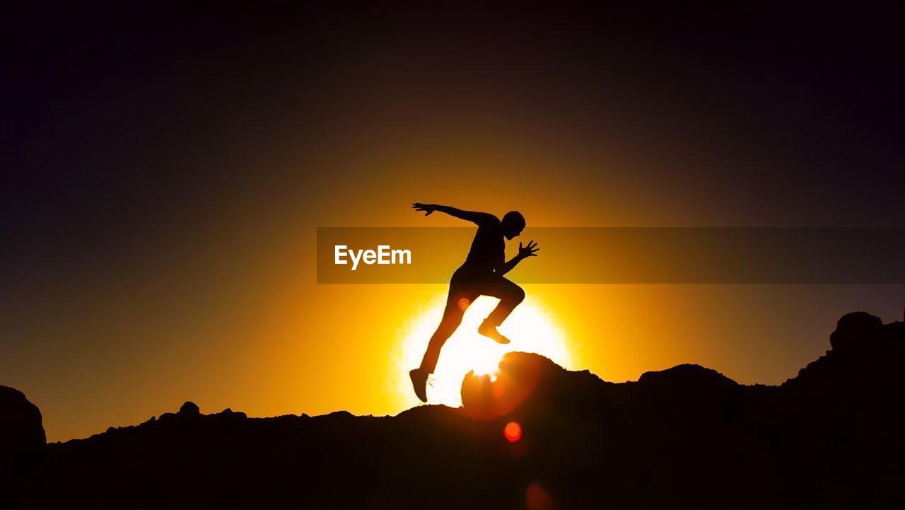 Silhouette man running against sky during sunset