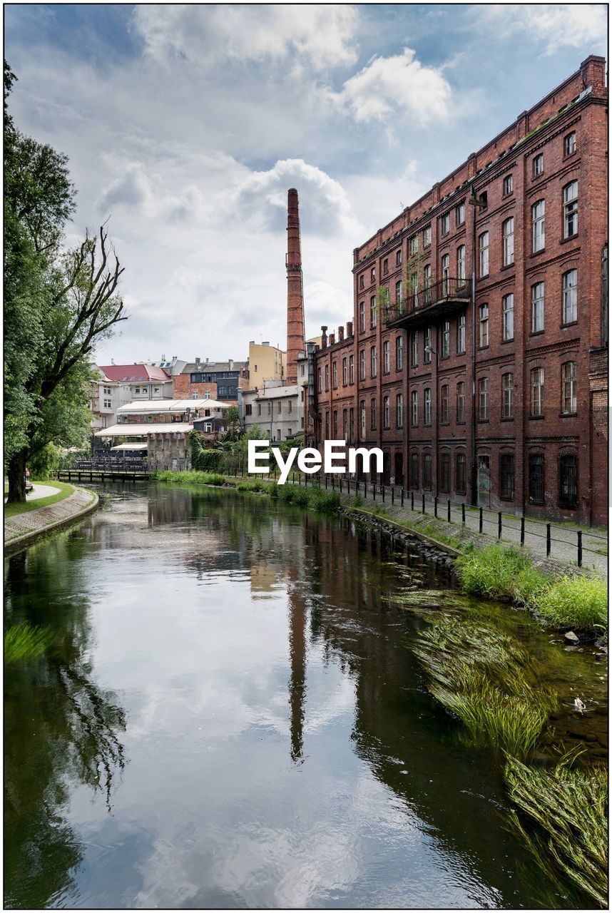 Canal amidst buildings in city against sky